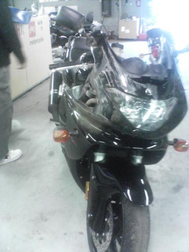 The first bike I received from the dealership - There's a story to go with this pic.  I purchased my bike from a local dealership, and went to pick it up the next day.  The dealership loaded my bike onto my bike trailer (it was raining and I was an inexperienced rider) and I did a walk around check to make sure it was strapped down.  I brought 4 straps with me....2 for the front and 2 for the back.  The dealership's employee only used 2 of my straps.  He strapped both sides of the front down, and left the back without any straps.  I protested, but the dealership assured me it was strapped properly and wasn't going anywhere.    As I left the dealership, I had to use the employee driveway behind the lot b/c this is where they had loaded the bike.  At the end of the drive, it dipped down about 2 inches where the drive met the road.  I pulled out, and lo and behold the bike fell off the trailer.  I couldn't slam on the breaks seeing as how I was in the middle of a busy highway, so I had to slowly pull off the side of the road (still within 50 feet of the dealership) while dragging the bike beside the trailer.  This is part of the damage that was caused, and of course, after threatening with a few lawsuits, the dealership had to cover the damages.  They wanted to fix the bike, but I made them give me the identical one in the showroom....and thus, I now have my baby w/o any scratches.  BTW- As for the wrecked bike, 2 months later it was sitting on the show room floor.  All exterior plastic was replaced, but instead of replacing everything behind the gauges that got chewed off, the dealership threw a smoked out windshield on it.  They didn't fix any of the damage to the chrome, or the big dent in the gas tank.  Some idiot bought it 2 weeks later for only $500 off the original purchase price!  See the other damage pics in my photos for more details!