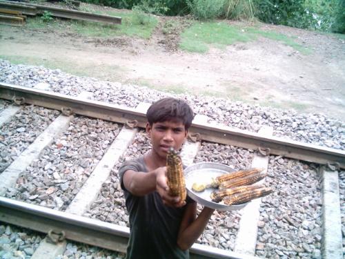 Indian young salesman. - A boy selling baked Corn just for 10cents, how much he must be earning out of it? This pic is taken from a Train window, Utter Pradesh Northen India, one the Indian Poor states, which was one the Richest states in 1857.