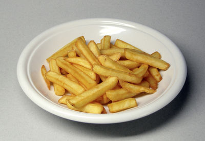 French fries - French fries have numerous variants, from 'thick-cut' to 'shoestring', 'joe joes,' 'crinkle', 'curly', and 'waffle-cut'. They can also be coated with breading and spices to create 'seasoned fries', or cut thickly with the skin left on to create 'potato wedges' or without the skin to create 'steak fries', essentially the American equivalent of the British 'chip'. Sometimes French fries are cooked in the oven as a final step in the preparation (having been coated with oil during preparation at the factory): these are often sold frozen, and are called 'oven fries.'  In France, the thick-cut fries are called 'pommes Pont-Neuf', cut about 10mm square. Thinner variants are 'pommes allumettes' (matchstick potatoes), 3-4mm square, 'pommes pailles' (straw potatoes), somewhat thinner, and 'pommes gaufrette' (waffle potatoes), cross cut. The two-bath technique is standard. (Bocuse)  In the British Isles, Australia, and elsewhere, the term French fries is only used by fast-food restaurants serving narrow-cut (shoestring) fries. Traditional chips in the United Kingdom are usually cut much thicker, typically between 3/8 and ½ inches square in cross section and cooked twice, making them less crunchy on the outside and fluffier on the inside. Since the surface-to-volume ratio is lower, they have a lower fat content. Chips are part of the popular British takeaway dish fish and chips. In Australia, the UK, Ireland, and New Zealand, very few towns or villages are without a chip shop.According to American culinary celebrity Alton Brown, Belgian pommes frites are usually fried in horse fat. Others maintain that traditionally, ox fat was used, although now nut oil is usually preferred for health reasons. Belgian fries must be fried twice, and about 10-13mm thick. Fries with Mayonnaise is a national dish of Belgium, often eaten without any side orders. Even the smallest Belgian town has a frietkot (a Dutch word literally meaning 'fries shack' which has also been adopted by the French speaking part of the country in addition to the French friterie; two alternate Dutch forms are frituur, from French friture, and frietkraam, which means about the same as frietkot).  Boardwalk fries, are brine soaked fresh-cut potatoes, that are quickly deep-fried in 100% peanut oil, served in paper buckets, sprinkled lightly with salt and malt vinegar. Perhaps one of the most famous vendors of boardwalk fries is Thrasher's French Fries of Ocean City, Maryland, United States, founded in 1929 by J.T. Thrasher. Thrasher's fries are often enjoyed with Old Bay crab seasoning, made available at the stand. The term 'Boardwalk Fries' was registered by brothers Dave and Fran DiFerdinando as a franchising company trademark in 1982. In 2006, they opened two Boardwalk Fries locations in Baltimore's Oriole Park at Camden Yards baseball field.  In Australia, New Zealand and South Africa, the word chips is used for both forms of fried potato; although the phrase hot chips unambiguously refers to French fries or chips.