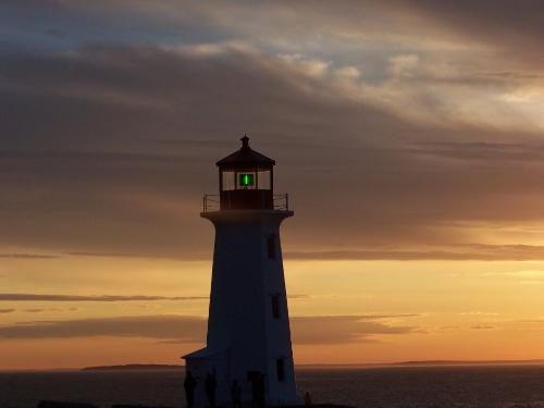 sunset nova scotia - a sunset over nova scotia with a lighthouse in the foreground