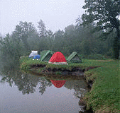 camping - tents set up next to the lake in the woods