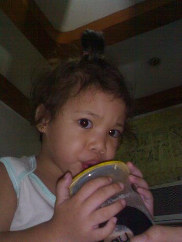 too big a straw to sip on! - She just woke up and her elder sister was sharing a glass of fruit shake with her in this pic. As you can see, the straw is just to big to sip on, hence the facial expression.