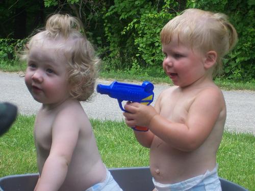 Stick &#039;em up! - Cousins playing with squirt guns on a hot summer day.