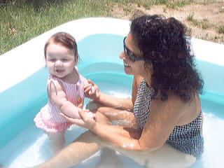 First pool time! - This is my daughter`s first time in the pool.  I think she was less than a year old.  It`s a winnie the pooh bathing suit.  Grandma went in with her (I know she doesnt even look like a grandma yet) and her daddy`s leaning towards the pool.  This was such a fun day.
