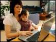 work at home online - A mother with her child on her lap work on her laptop as she work from home