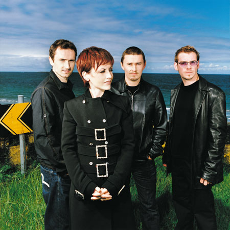 The Cranberries Picture Gallery - Originally, the Cranberries were a band called the Cranberry Saw Us. Brothers Noel and Mike Hogan (guitar and bass, respectively) formed the band in Limerick, Ireland, with drummer Fergal Lawler in 1990. Following the departure of the group's original singer, Niall, the trio placed an advertisement for a female singer. Dolores O'Riordan responded to the advertisement and auditioned by writing lyrics and melodies to some of the band's existing demos. When she returned with a rough version of 'Linger,' the group hired her on the spot. Shortly after she joined, the band recorded a demo tape which they sold in record stores throughout Ireland. After the original run of 300 copies sold out, the group truncated their name to the Cranberries and sent another demo tape, which featured early version of both 'Linger' and 'Dreams,' to record companies throughout the U.K. The tape was made at Xeric studios, which was run by Pearse Gilmore, who would later become their manager. At the time the tape was made, all of the members were still in their late teens.