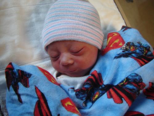 My little Superman - This my sons first day of life. He is my little man. The blanket was hand made by cousin.