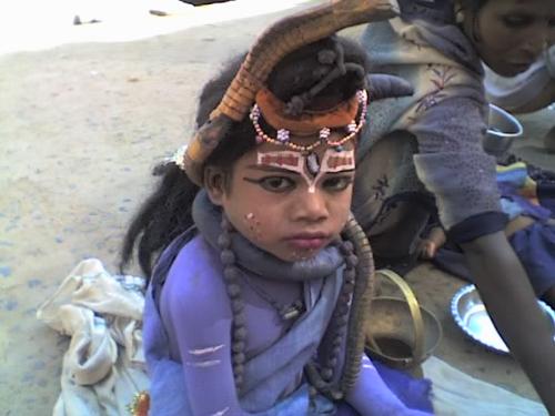 childcare - a child in a get-up of indian god 'sankar( shiv ji)'. but look at his face, he dont want to do that. this is his nursery..