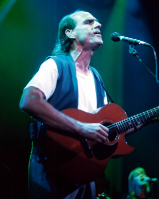 James Taylor - When people use the term 'singer/songwriter' (often modified by the word 'sensitive') in praise or in criticism, they're thinking of James Taylor. In the early '70s, when he appeared with his introspective songs, acoustic guitar, and calm, understated singing style, he mirrored a generation's emotional exhaustion after tumultuous times. Just as Bing Crosby's reassuring voice brought the country out of the Depression and through World War II, Taylor's eased the transition from '60s activism and its attendant frustrations into the less political, more inward-looking '70s. He was rewarded with a series of hit albums and singles (surprisingly, many of the latter were covers of old songs rather than his own compositions), and he managed to survive his initial fame to achieve lasting popularity. He continued to tour successfully for decades, and, starting with his 1970 breakthrough Sweet Baby James, all but one of his regular album releases for the rest of the century went gold or platinum, while his 1976 Greatest Hits album achieved a diamond certification reflecting sales of more than ten million copies.Taylor was the son of Dr. Isaac and Gertrude Taylor. His three brothers Alex (1947-1993), Livingston, and Hugh - and his sister Kate - all became musicians and recorded albums of their own. In 1951, Dr. Taylor was appointed dean of the medical school at the University of North Carolina at Chapel Hill, and the family moved from New England to the South. Taylor studied cello as a child, but first took up the guitar in 1960. In 1963, he began attending Milton Academy, a prep school in Massachusetts. That summer, he met fellow guitarist Danny 'Kootch' Kortchmar while staying on Martha' s Vineyard, and the two formed a folk duo. Taylor dropped out of school at 16 and formed a band with his brother Alex. Having moved to New York, he suffered from depression and checked himself into McLean Psychiatric Hospital in Massachusetts, a stay that would inspire some of his early songs. While there, he earned a high school diploma. Upon release, he returned to New York in 1966 and formed a new group, the Flying Machine, with Kortchmar and Joel O'Brien. The band played in Greenwich Village and was signed to a fledgling record label, Rainy Day Records (the name taken from Taylor' s song 'Rainy Day Man'). It released one single, 'Brighten Your Night with My Day' / 'Night Owl,' both songs written by Taylor. The record was unsuccessful, and the band broke up in the spring of 1967.