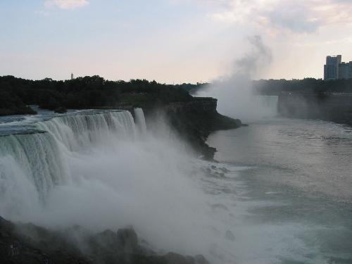 niagara falls - Niagara Falls is a set of massive waterfalls located on the Niagara River in eastern North America, on the border between the United States and Canada. Niagara Falls (French: les Chutes du Niagara) comprises three separate waterfalls: the Horseshoe Falls (sometimes called the Canadian Falls), the American Falls, and the smaller, adjacent Bridal Veil Falls. While not exceptionally high, Niagara Falls is very wide. With more than 6 million cubic feet (168,000 m³) of water falling over the crestline every minute[1] in high flow, and almost 4 million cubic feet (110,000 m³) on average, it is the most powerful waterfall in North America.[2] Niagara Falls is located about twenty minutes away from the U.S. city of Buffalo and about 90 minutes from the Canadian city of Toronto.  Some sources erroneously quote that Niagara Falls has an average flow of about 12 million cubic feet per minute (200,000 cu ft/s) or even slightly more. This figure is derived from the average rate of flow (202,000 cu ft/s) of the Niagara River. This volume would pass over the falls if there were no hydroelectric water diversion upstream from the falls; however, water is diverted continuously from Niagara and this figure is approximately three times the actual average flow volume over the falls.  Niagara Falls is renowned for its beauty, and is both a valuable source of hydroelectric power and a challenging project for environmental preservation. A popular tourist site for over a century, the natural wonder is shared between the twin cities of Niagara Falls, Ontario and Niagara Falls, New York.