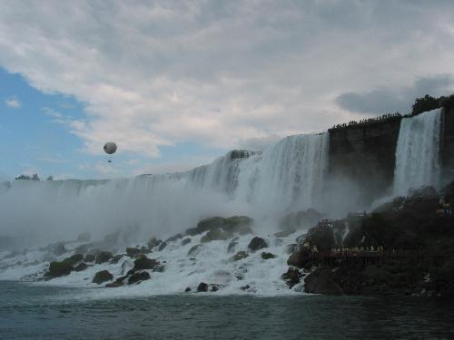 niagara falls - Niagara Falls is a set of massive waterfalls located on the Niagara River in eastern North America, on the border between the United States and Canada. Niagara Falls (French: les Chutes du Niagara) comprises three separate waterfalls: the Horseshoe Falls (sometimes called the Canadian Falls), the American Falls, and the smaller, adjacent Bridal Veil Falls. While not exceptionally high, Niagara Falls is very wide. With more than 6 million cubic feet (168,000 m³) of water falling over the crestline every minute[1] in high flow, and almost 4 million cubic feet (110,000 m³) on average, it is the most powerful waterfall in North America.[2] Niagara Falls is located about twenty minutes away from the U.S. city of Buffalo and about 90 minutes from the Canadian city of Toronto.  Some sources erroneously quote that Niagara Falls has an average flow of about 12 million cubic feet per minute (200,000 cu ft/s) or even slightly more. This figure is derived from the average rate of flow (202,000 cu ft/s) of the Niagara River. This volume would pass over the falls if there were no hydroelectric water diversion upstream from the falls; however, water is diverted continuously from Niagara and this figure is approximately three times the actual average flow volume over the falls.  Niagara Falls is renowned for its beauty, and is both a valuable source of hydroelectric power and a challenging project for environmental preservation. A popular tourist site for over a century, the natural wonder is shared between the twin cities of Niagara Falls, Ontario and Niagara Falls, New York.
