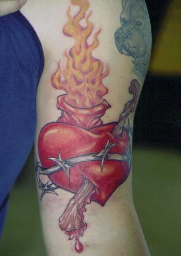 Heart of Kane - 5.5 hours.  The clients name is Kane, so I suggested to 'dress-up' his sacred heart design that we 'peirce the heart, with the 'cane' of a wise man.  There is also a hidden skull image in the flames at the top of the heart. Razor wire instead of the traditional wrapped vines/thorns wrapping around it...and we have one cool tattoo!